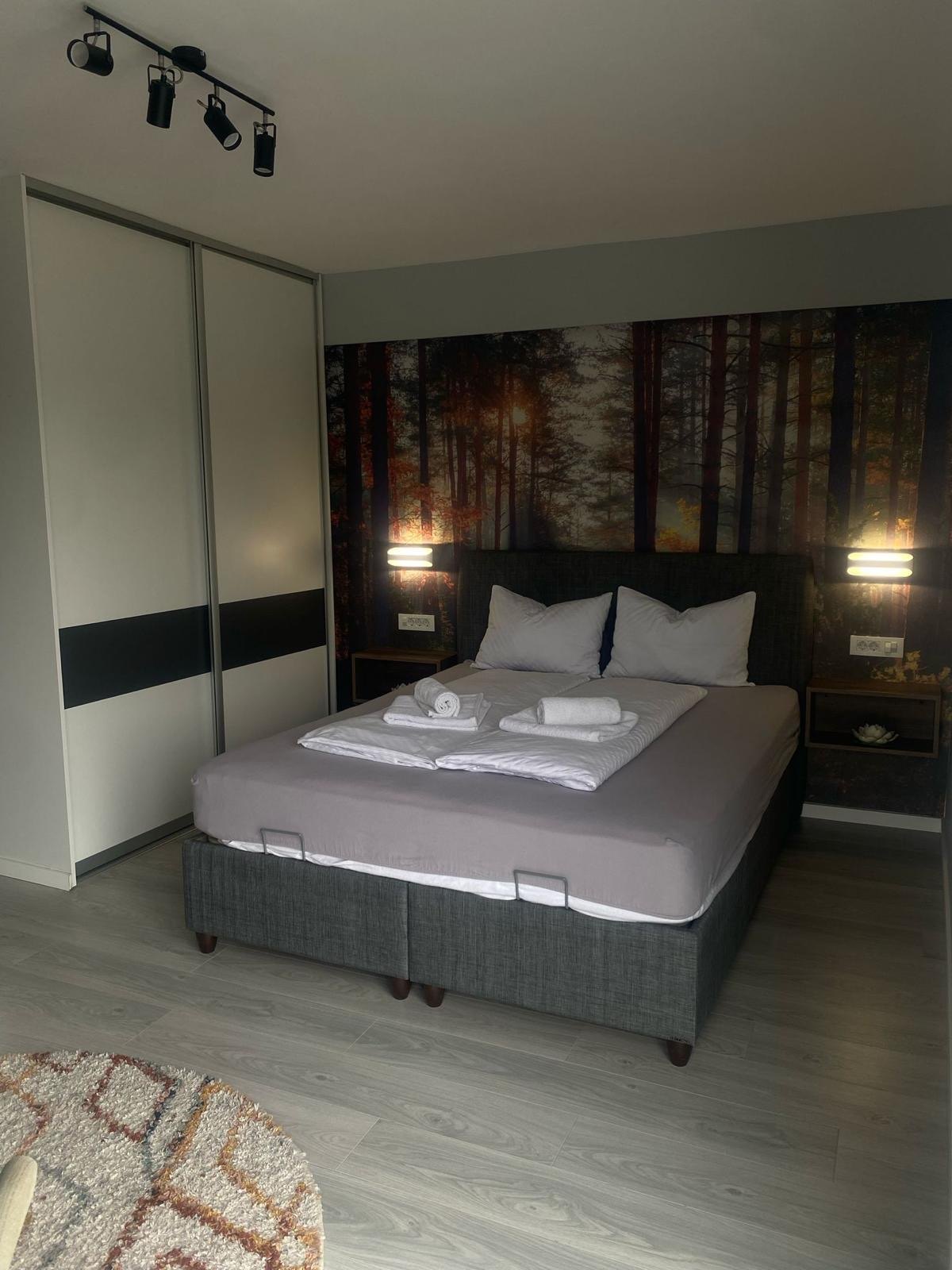 Bračni krevet u Delux apartmanu s dekoracijom šume iza uzglavlja